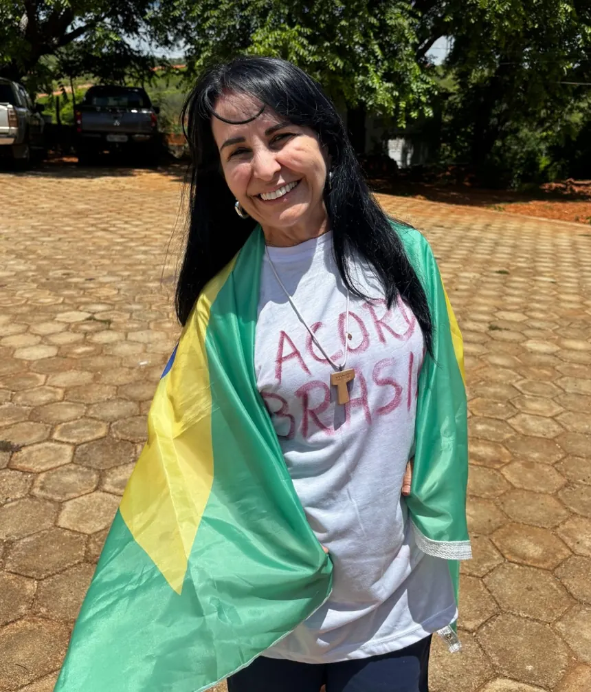 Alcyvania Pinheiro sorrindo com a bandeira do Brasil sobre os ombros